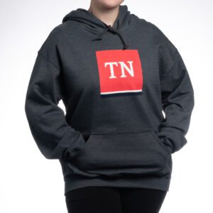 A person wearing a black hoodie with a red tag on it.